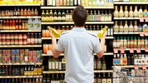 Young man looking at bottles of oil in market, rear view, close-up